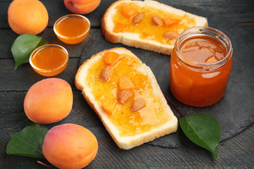 Two slices of bread and jar with apricot jam on table