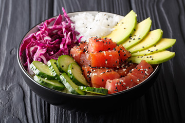 Organic food: tuna poke bowl with rice, fresh cucumbers, red cabbage and avocado close-up....