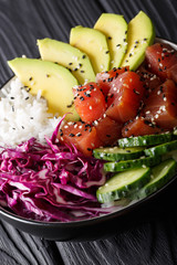 Hawaiian tuna poke bowl with avocado, red cabbage, cucumber and sesame seeds. vertical