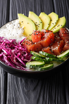 Tuna poke bowl with rice, cucumber, red cabbage and avocado close-up. vertical