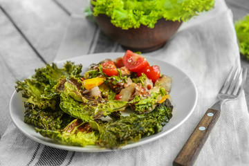 Plate with lettuce chips and salad on table