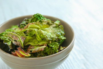Bowl with lettuce chips on wooden table