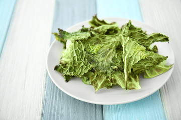Plate with lettuce chips on wooden table