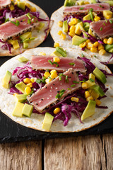 Mexican tortilla with tuna, red cabbage, corn, avocado and onions closeup on table. vertical