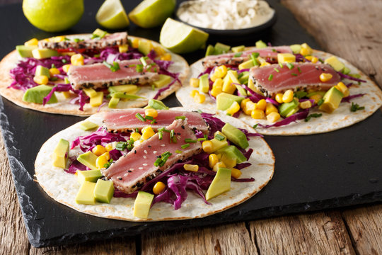 Tacos with tuna steak and fresh vegetables close-up on the table. horizontal