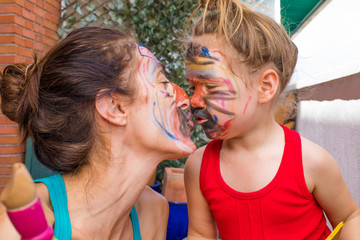mother and little daughter with painted face kissing