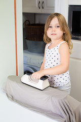 smiling little girl ironing in kitchen