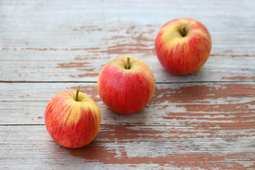 three apples on a wood table, diagonal row