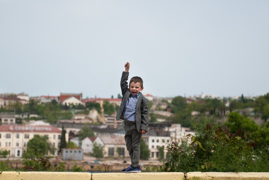 jubilant little boy in a jacket raised one hand up