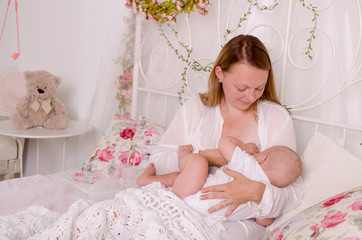 Obraz na płótnie Canvas Breastfeeding baby. Young mother holding her newborn child. Mom nursing baby. Woman and new born boy in white bedroom.