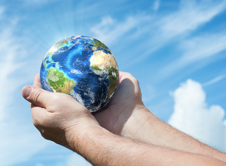 Globe in human hand against blue sky. Environmental protection concept. Ecology concept. Elements of this image furnished by NASA
