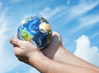 Globe in human hand against blue sky. Environmental protection concept. Ecology concept. Elements...