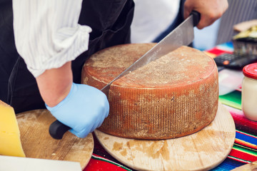 a person cut a cheese in the cheese market.