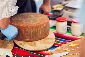 a person cut a cheese in the cheese market.
