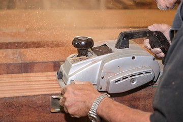 Selective on electric planer is being worked with senior carpenter in carpentry workshop. Shallow...