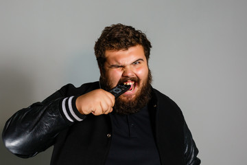 Nervous or irritated man holding remote control and try to watching tv isolated on gray background