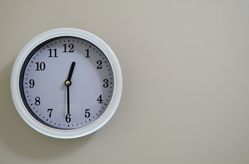 Time of the wall clock hung on a wall is 12:30.