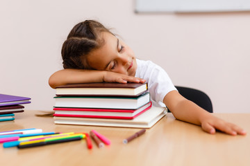 Adorable little girl sleeping on a stack of books over white background