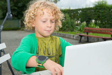 little blond boy using a laptop, outdoors