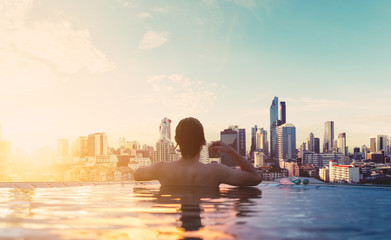a man relax in swimming pool in sunrise, on rooftop in the city © SasinParaksa