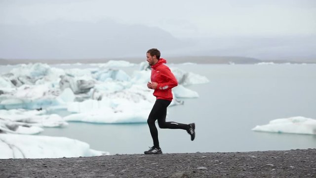 Running fit young man jogging by icebergs. Sporty male runner is in sportswear. He is running in nature. Fit athlete living healthy active lifestyle training outside in amazing landscape.
