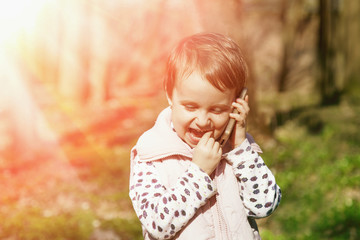 Happy cute little child girl talking phone outdoors (Happy childhood, family, communication concept)