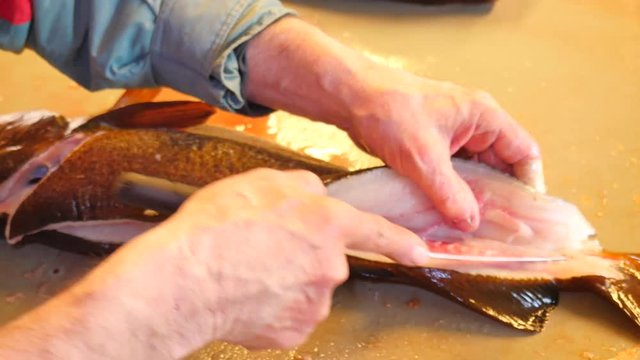 The operator makes dorsal cut with very sharp knife. Hands control viscera and separation of fillets from bones. Hands cut fins, gills, check fish livers, removing guts. Freshly caught fish 