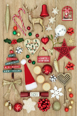 Fototapeta na wymiar Christmas decorative symbols with new and old fashioned bauble decorations, holly, mistletoe, gingerbread biscuit and mince pies on light oak wood background.