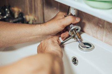 Man services and repairs leaky old faucet on the tap in the bathroom - 170027706