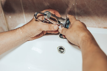 Man repair and fixing leaky new faucet in bathroom