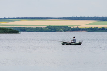 The fisherman on a boat catches fish on a pond