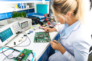 Female electronic engineer testing computer motherboard in laboratory - obrazy, fototapety, plakaty