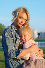 Fototapeta na wymiar Urban portrait of mother with daughter in sunset