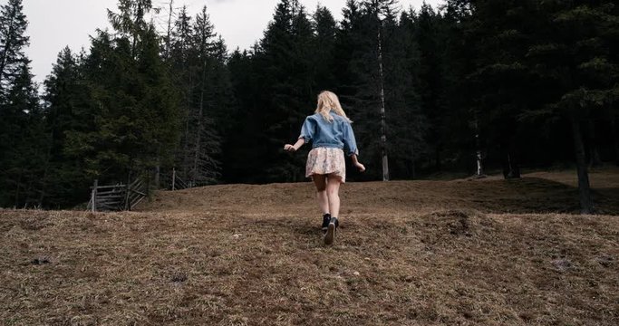 Joyful young girl running on the field, slow motion. 4k. The model moves and feels happy.
