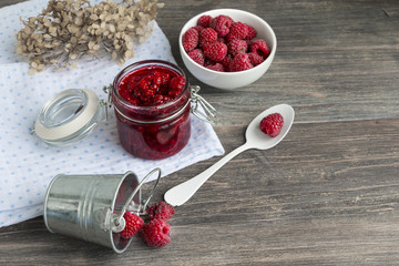 Fresh raspberries in bowl, raspberry jam on wooden table. Copy space.