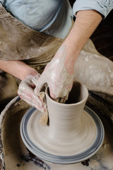 pottery, workshop, ceramics art concept - closeup on male hands sculpt new utensil with a tools and water, man's fingers work with potter wheel and raw fireclay, front close view