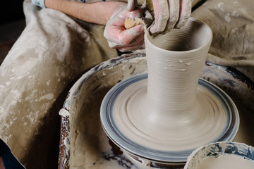 pottery, workshop, ceramics art concept - closeup on male hands sculpt new utensil with a tools and water, man's fingers work with potter wheel and raw fireclay, front close view
