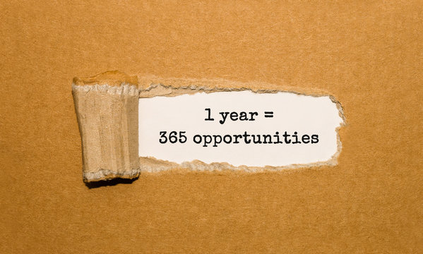 The text 1 year is 365 opportunities appearing behind torn brown paper