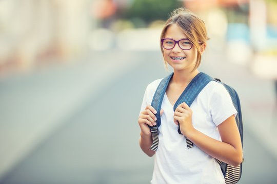 Schoolgirl with bag, backpack. Portrait of modern happy teen school girl with bag backpack. Girl with dental braces and glasses