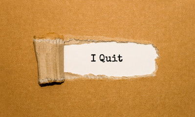 The text I Quit appearing behind torn brown paper