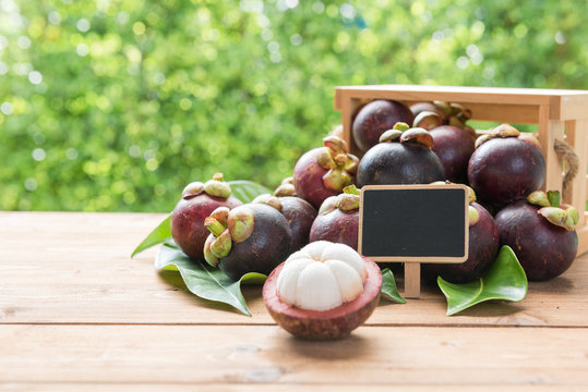 Fresh Mangosteen fruie on wood table with green blurred background,queen of fruit in Thailand,cold fruit