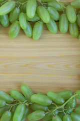 Frame of green grapes on wooden background. Copy space