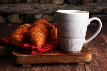 Coffee white cup, croissants on brown wooden background. Breakfast concept