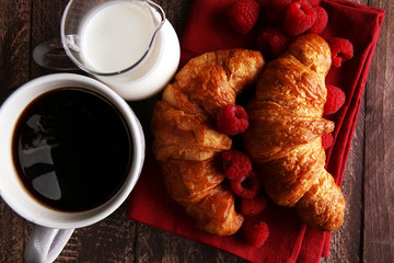 Coffee white cup, croissants on brown wooden background. Breakfast concept