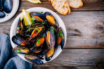 Delicious seafood mussels with with sauce and parsley.  Lemon and baguette . Clams in the shells. - obrazy, fototapety, plakaty