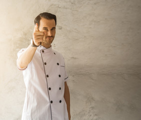 Handsome Attractive caucasian man chef smiling and pointing posing on a gray wall background,with copyspace