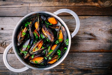 Delicious seafood mussels with with sauce and parsley.  Lemon and baguette . Clams in the shells.