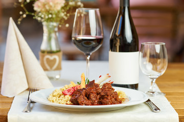 Beef stew in a restaurant with red wine in the background