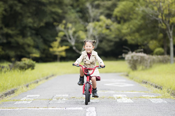 Fototapeta premium Little girl riding a red bicycle