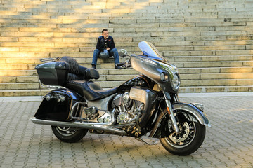 Obraz na płótnie Canvas Motorcyclist with helmet sitting on the steps behind his motorbike